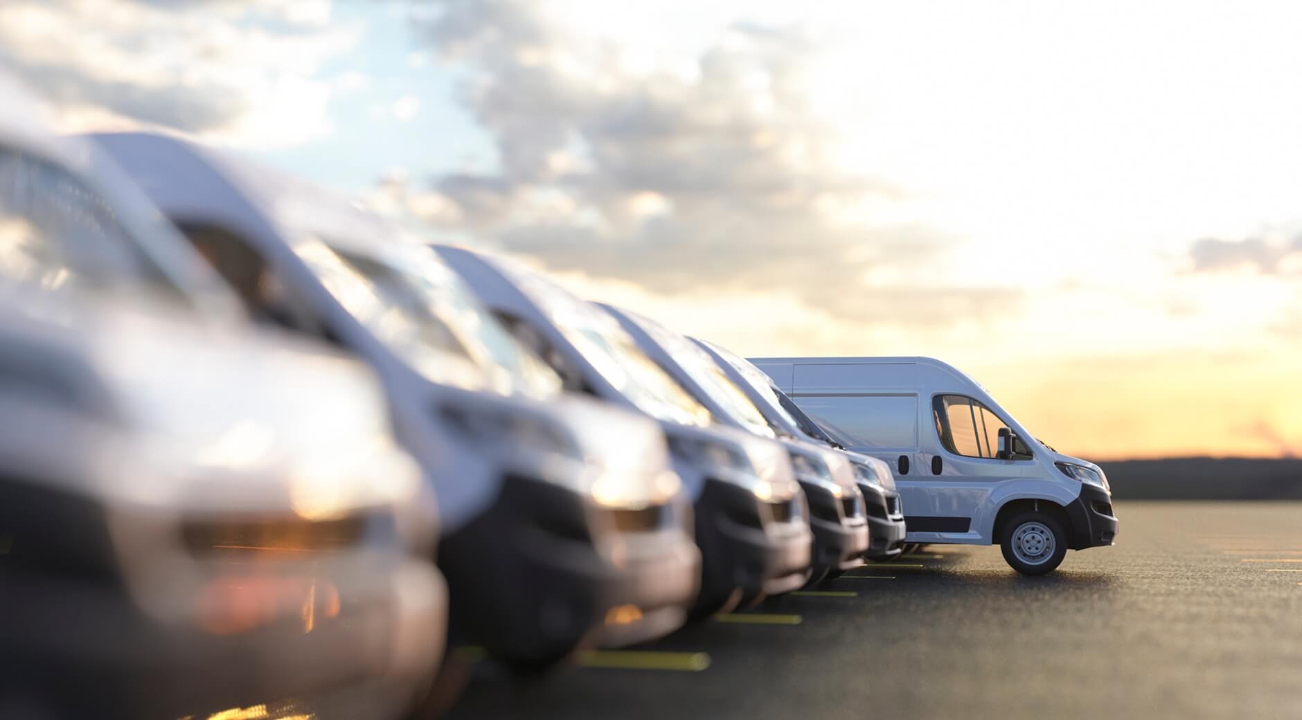 Row of delivery vans parked side by side at sunset