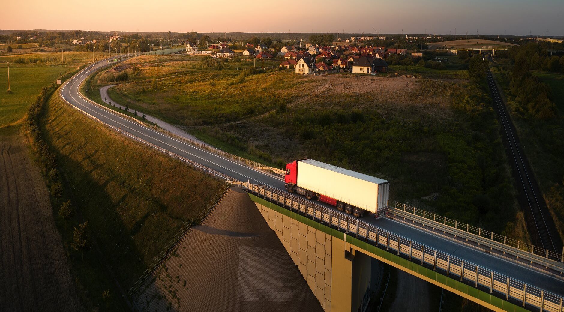 Semi truck driving across a bridge on a rural highway at sunset