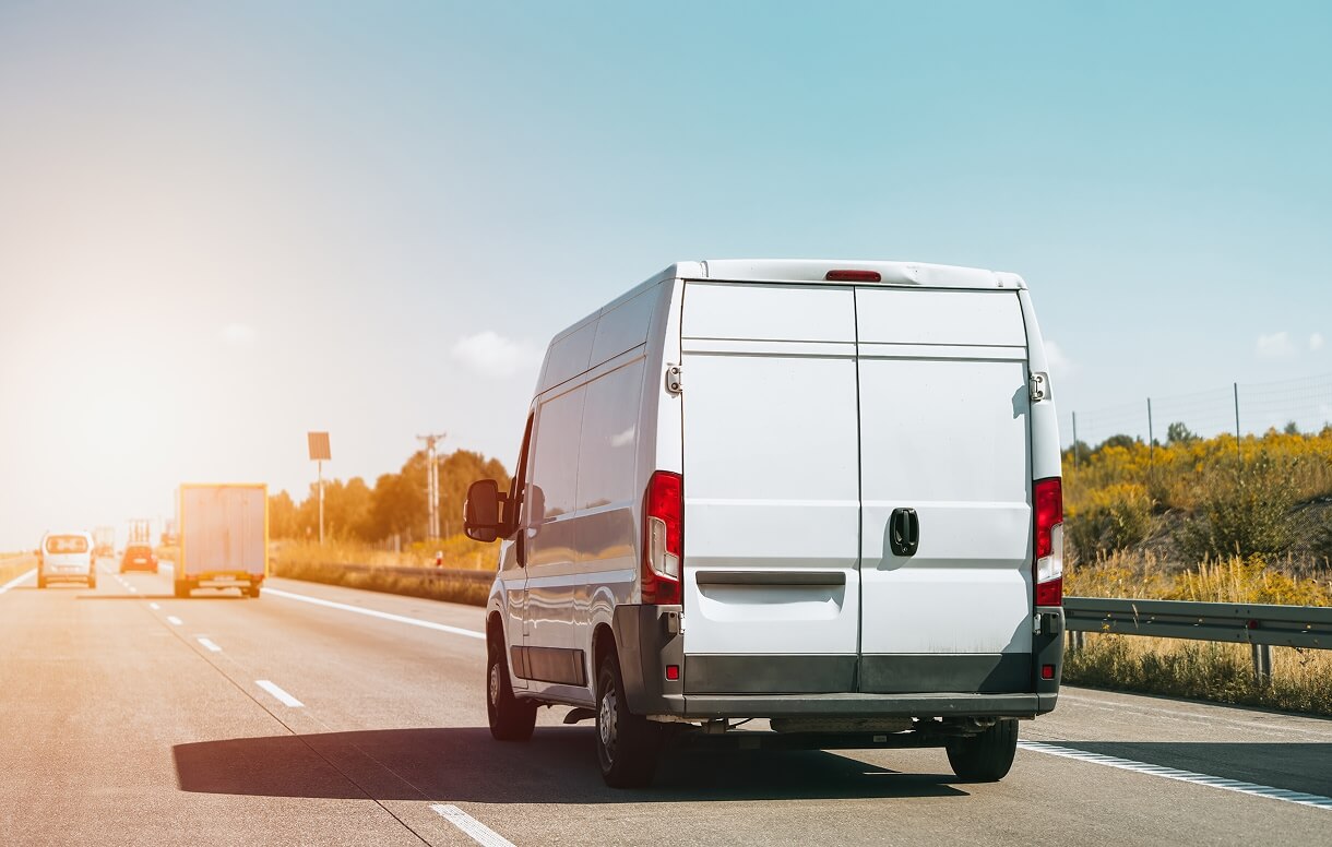 White delivery van driving on a highway at sunset